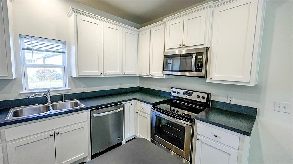 a kitchen with stainless steel appliances granite countertop white cabinets and a stove top oven