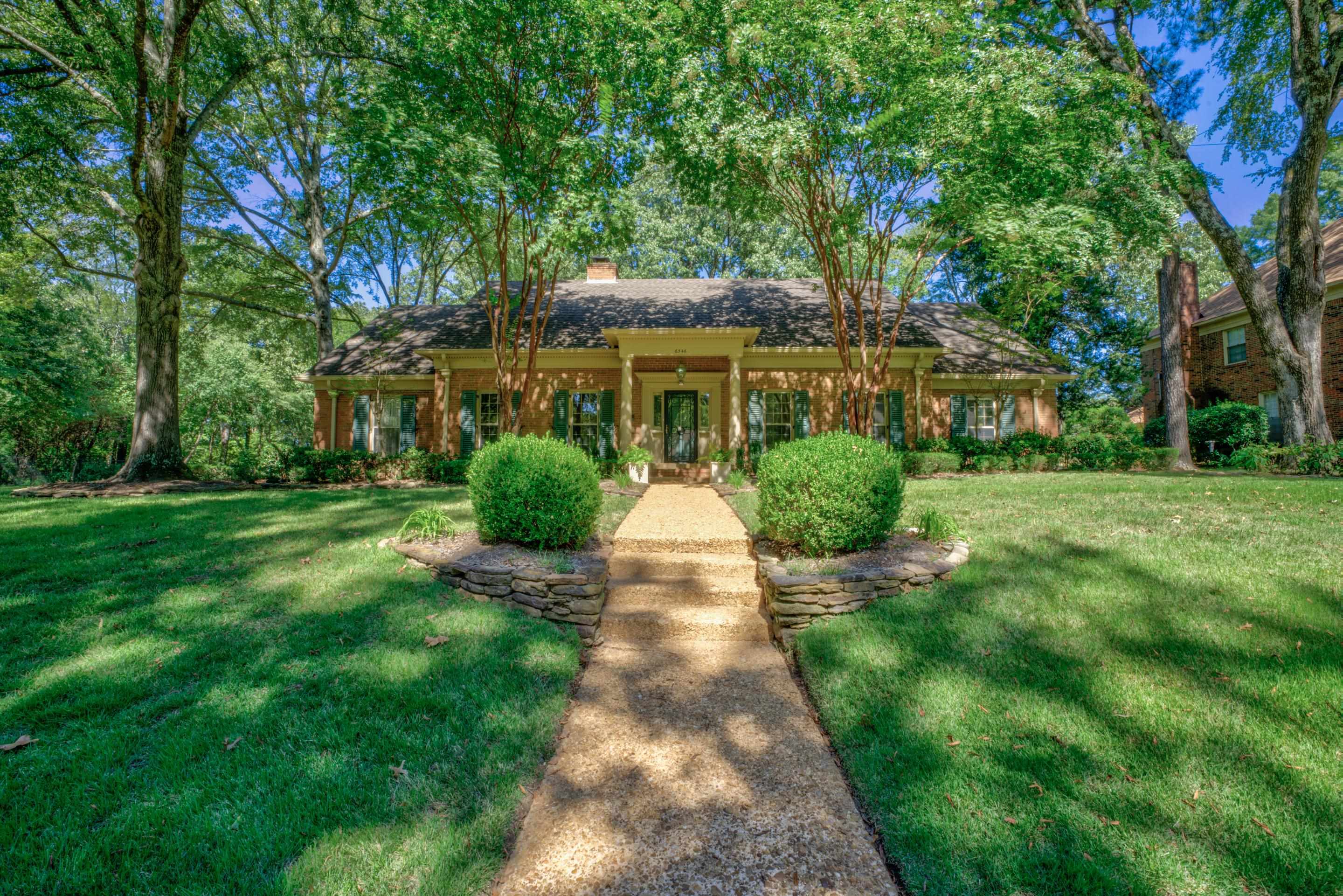 a front view of a house with yard and green space