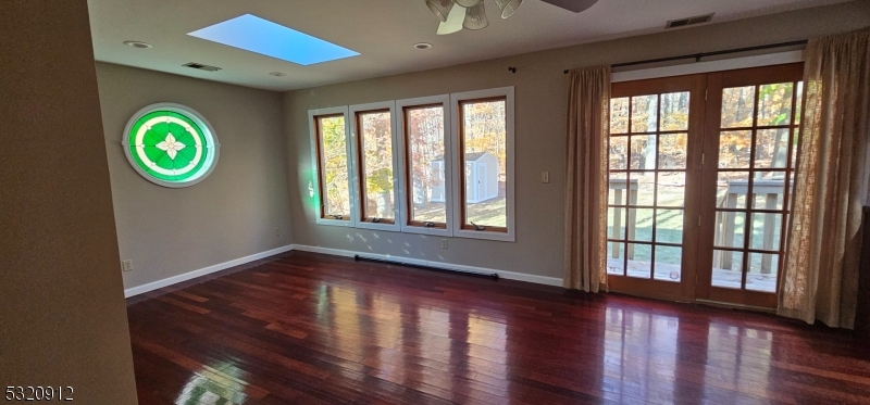 a view of an empty room with window and wooden floor