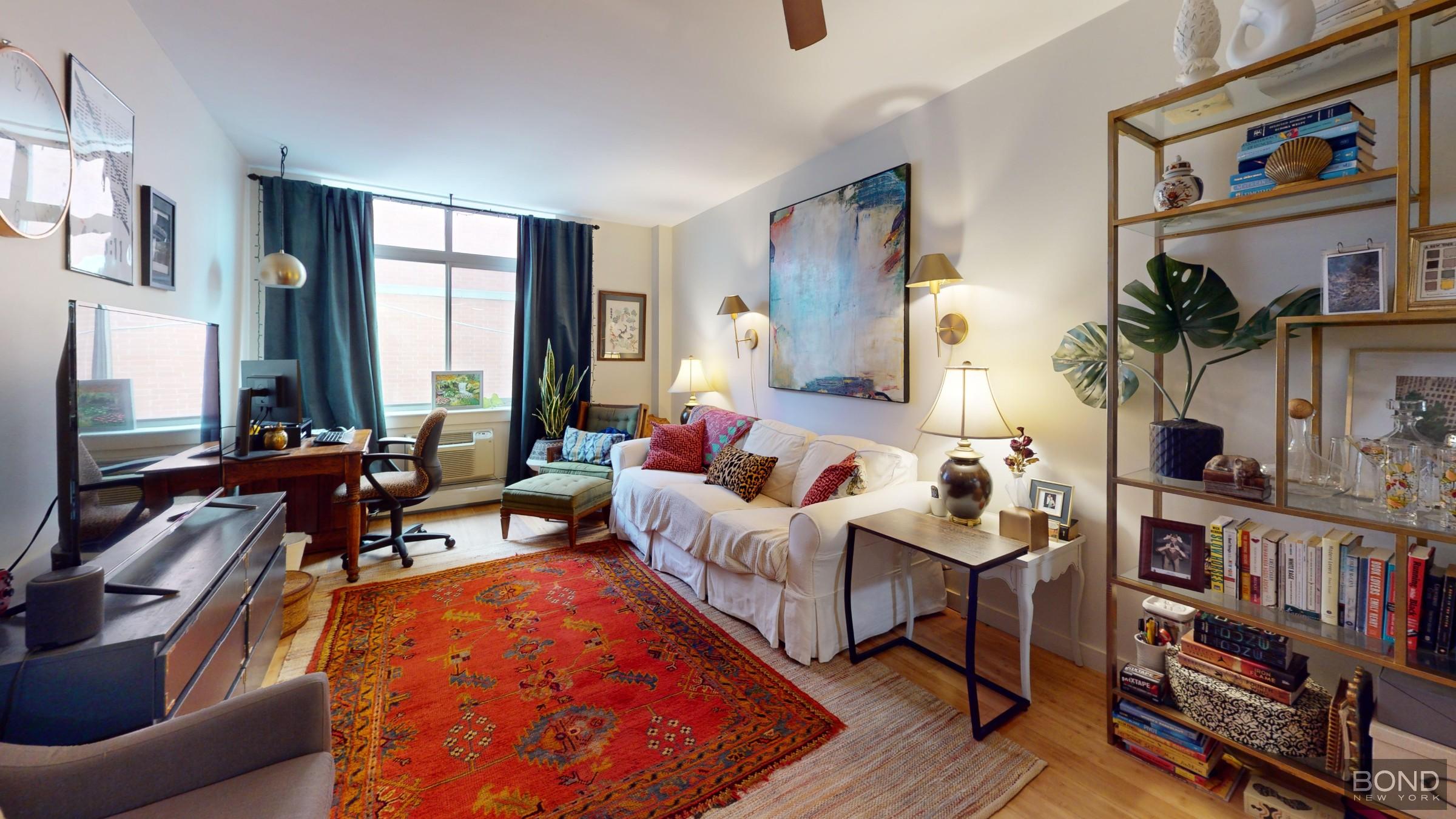 a living room with furniture a bookshelf and a window