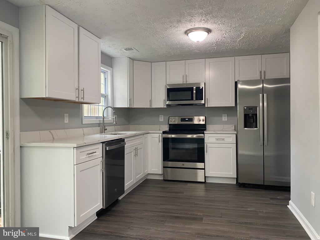 a kitchen with cabinets stainless steel appliances and wooden floor