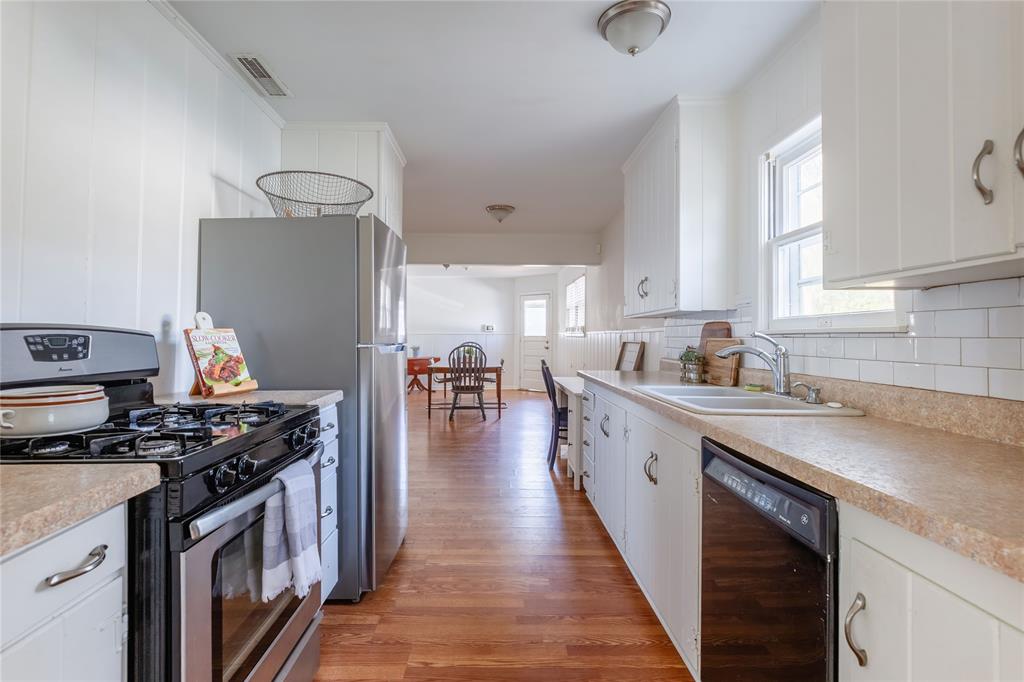 a kitchen with stainless steel appliances a sink dishwasher stove and oven with wooden floor