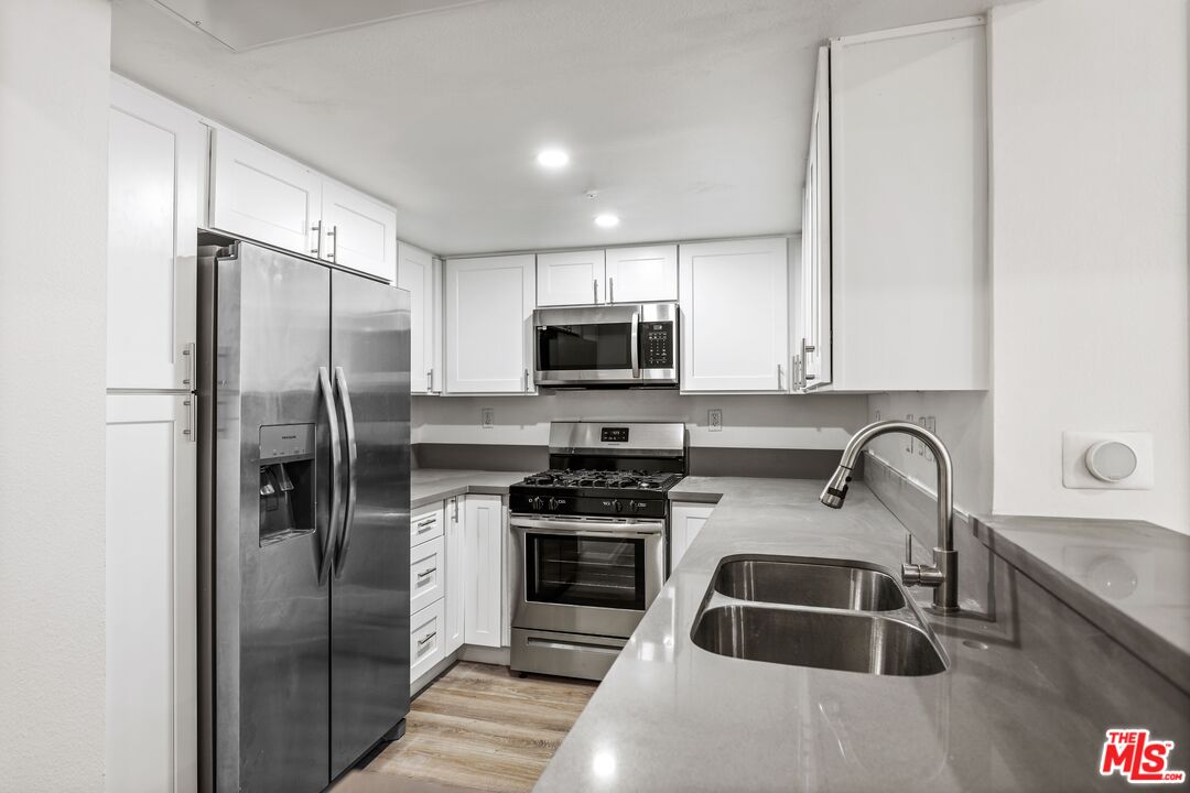 a kitchen with granite countertop a stove a refrigerator and a sink