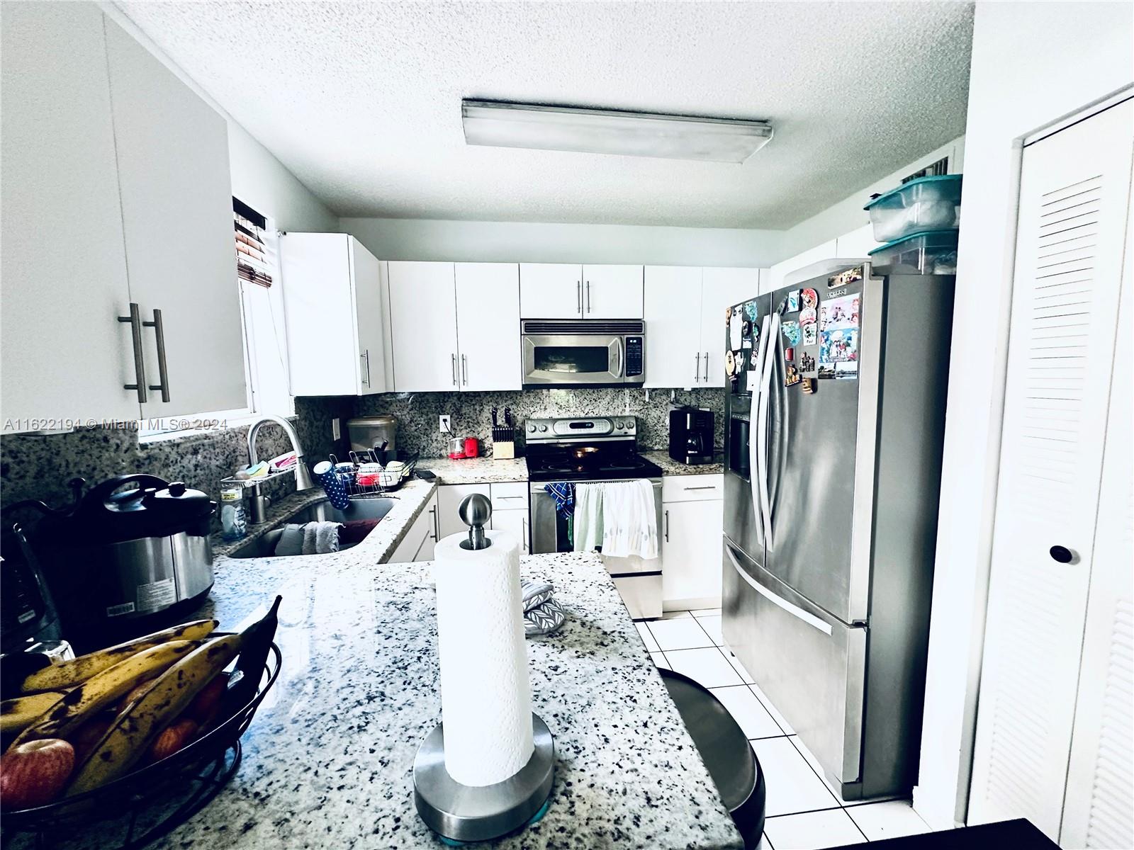 a kitchen with stainless steel appliances granite countertop a refrigerator stove top oven a sink and dishwasher