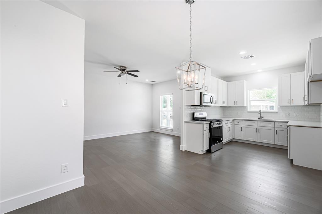 a large kitchen with white cabinets stainless steel appliances and a chandelier