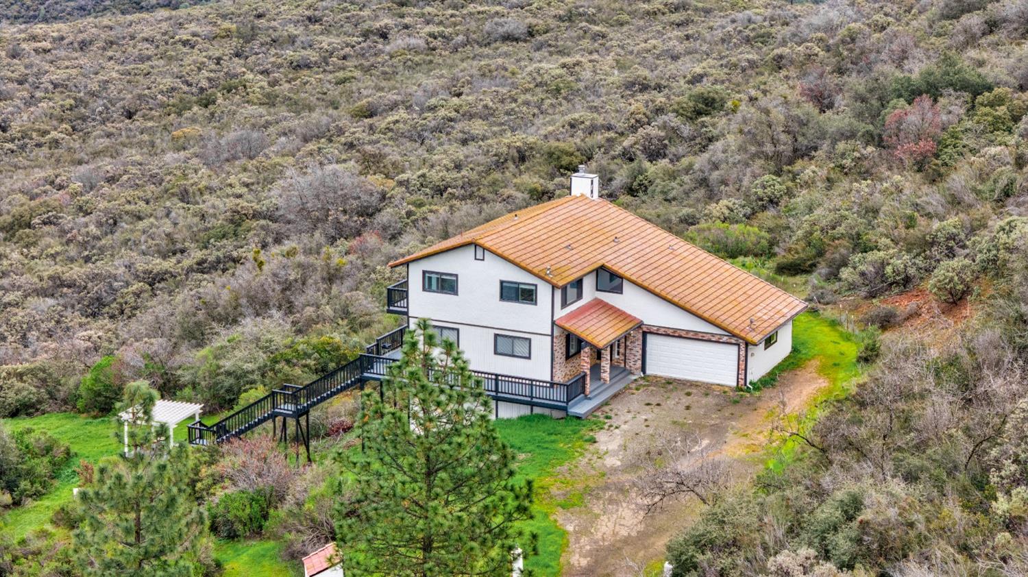 a aerial view of a house with yard and trees in the background