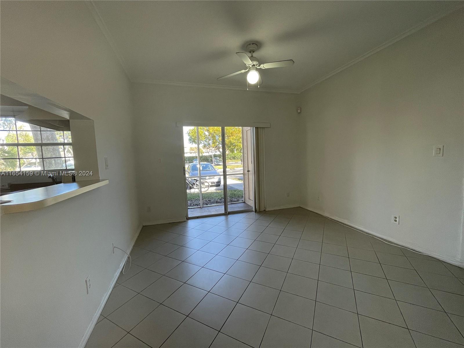 an empty room with chandelier fan and windows