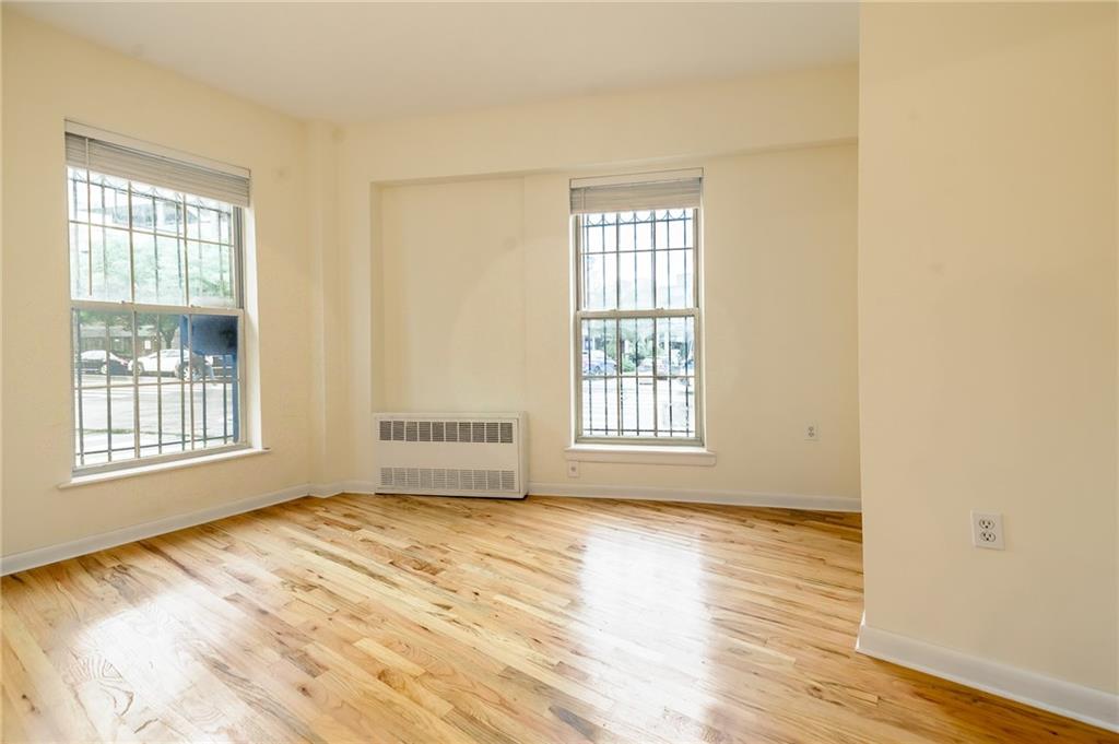 a view of an empty room with a window and wooden floor