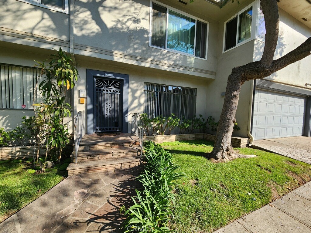 a view of a house with potted plants and a yard