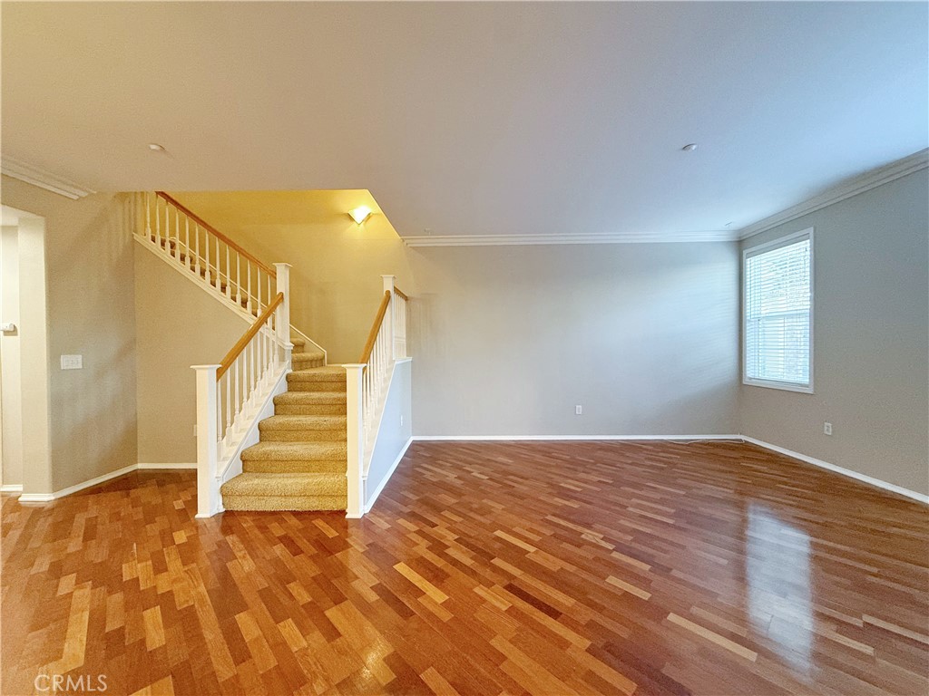 a view of an empty room with wooden floor and stairs