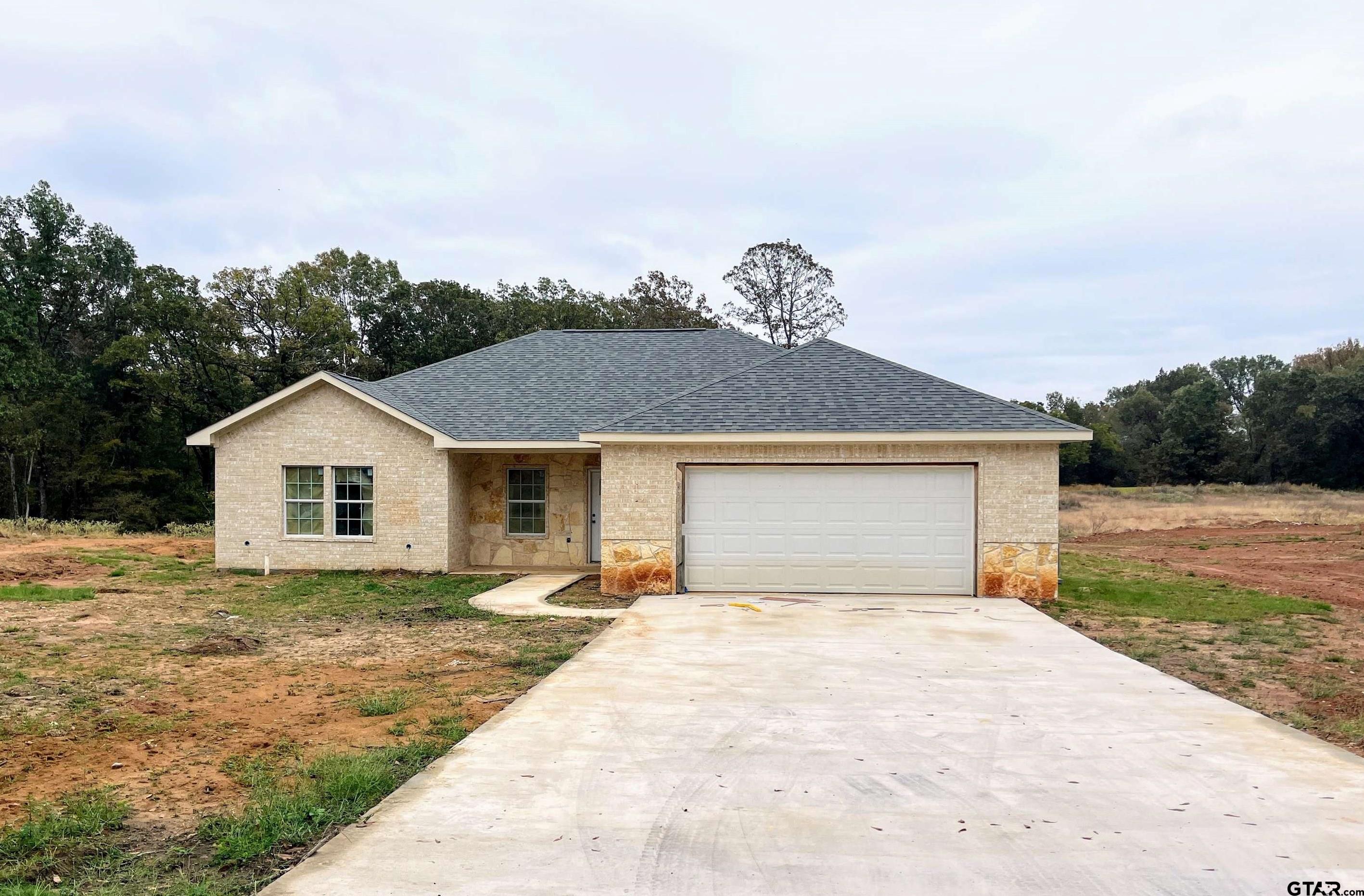 a front view of house with yard and trees in the background