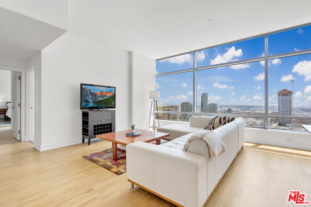 a living room with furniture a floor to ceiling window and a flat screen tv