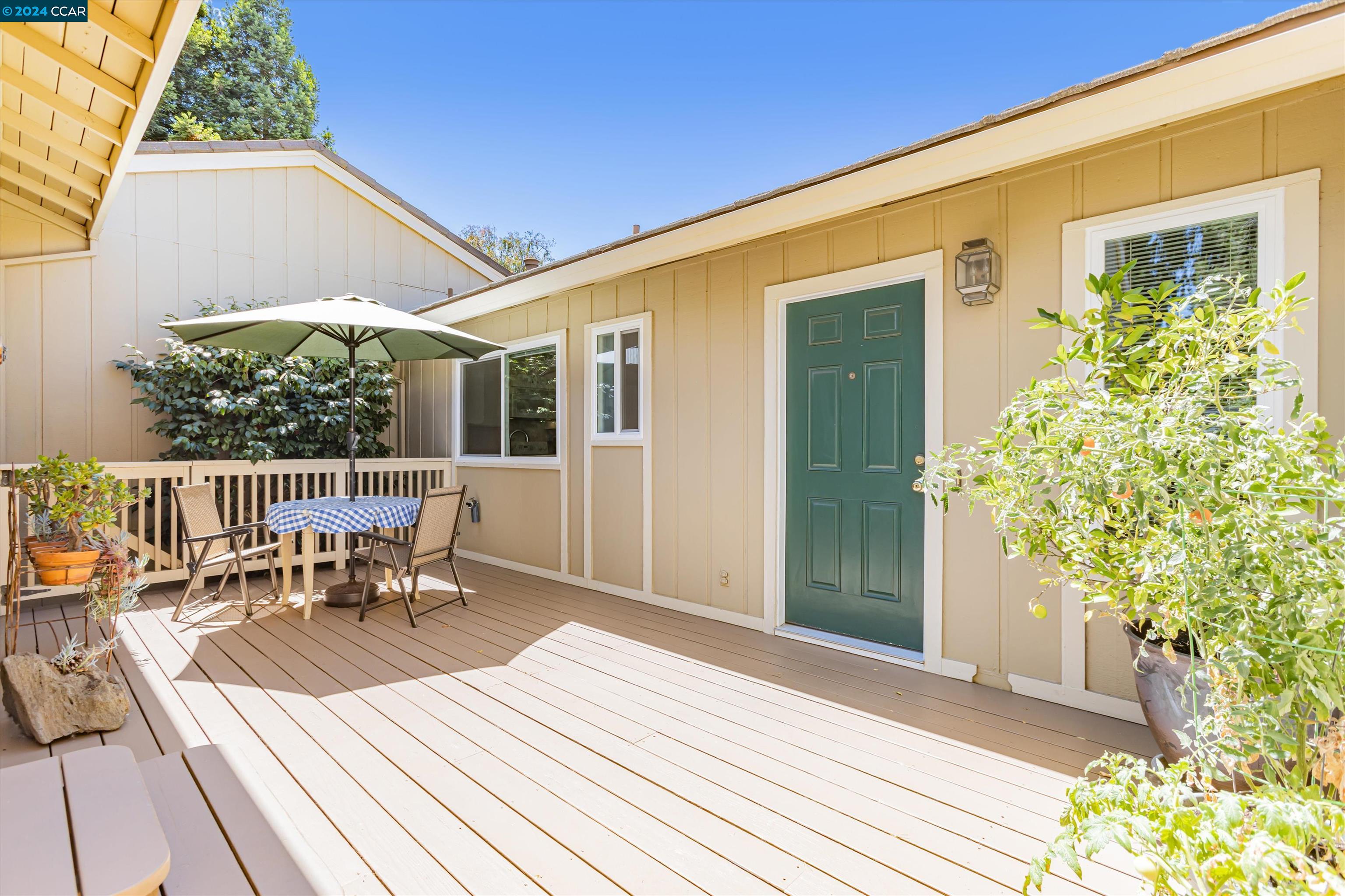 a view of a patio with table and chairs with wooden floor and fence