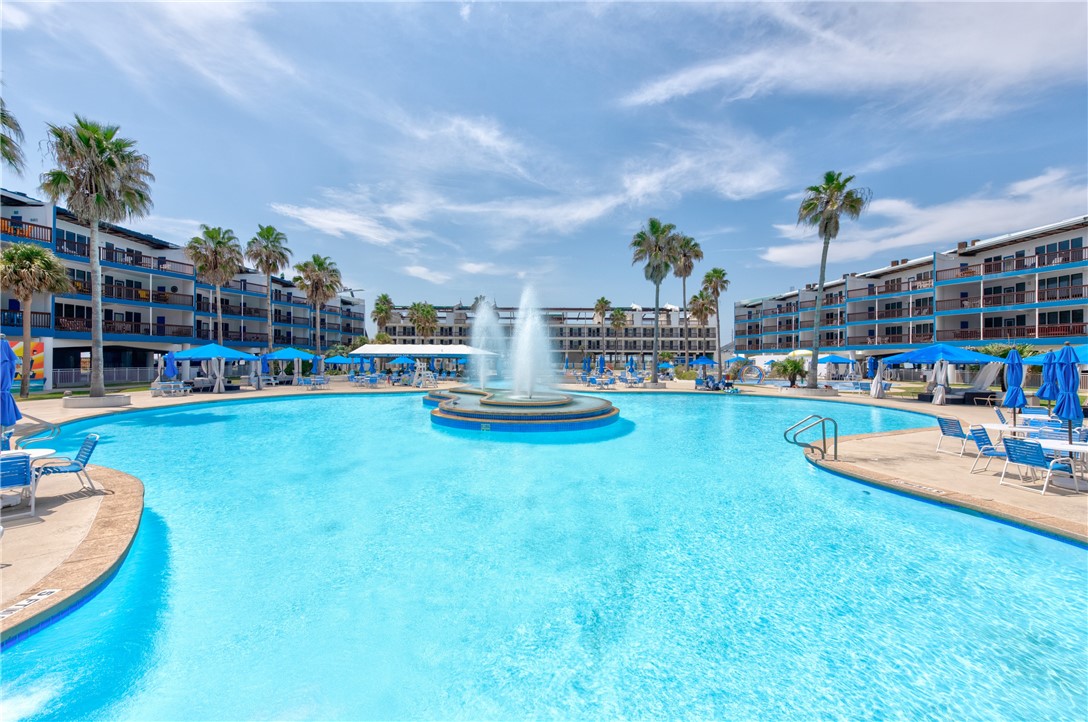 a view of a swimming pool with lawn chairs and a fire pit