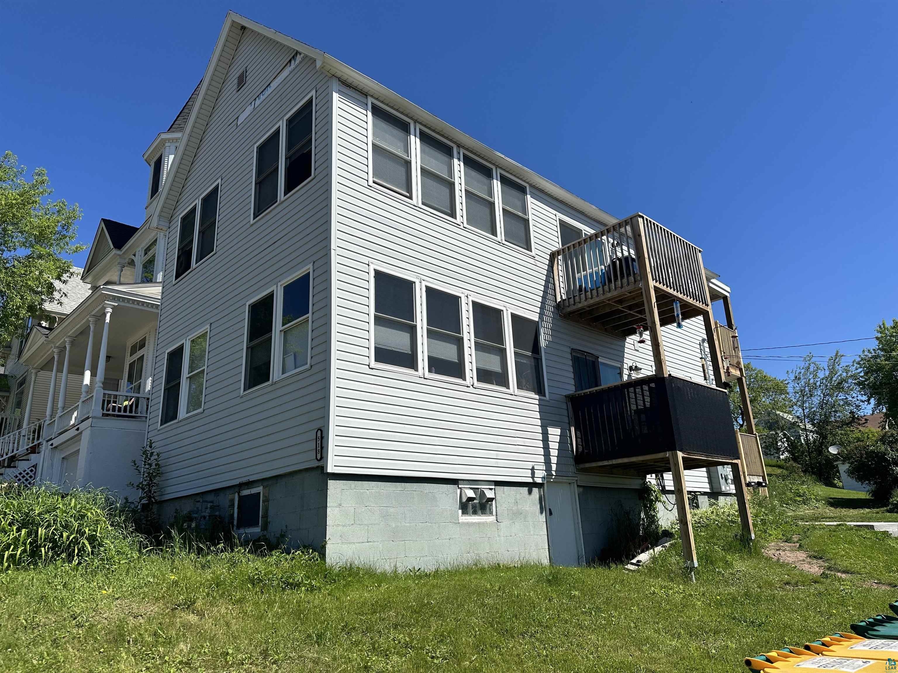 View of side of property with a yard and a balcony