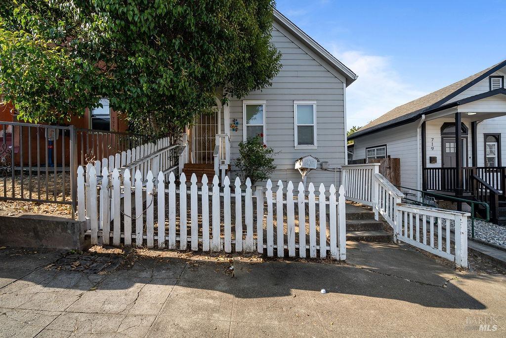 a front view of white house with wooden fence