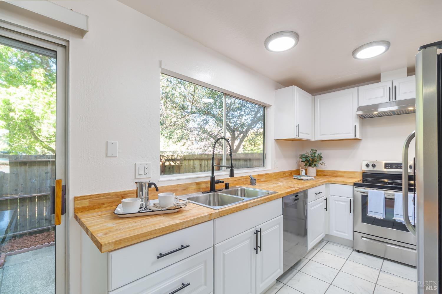 Discover the heart of the home in this stunning kitchen, featuring brand-new cabinets, a sleek butcher block countertop, and stainless-steel appliances. A large window bathes the space in natural light, making it both functional and inviting.