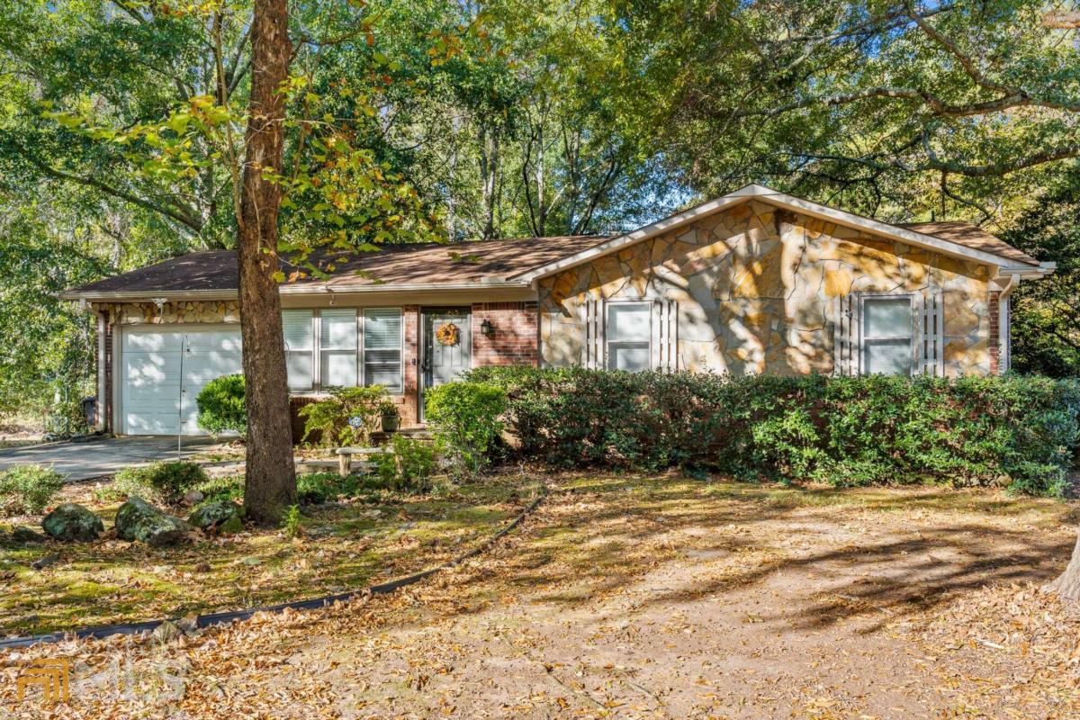 a backyard of a house with large trees and plants