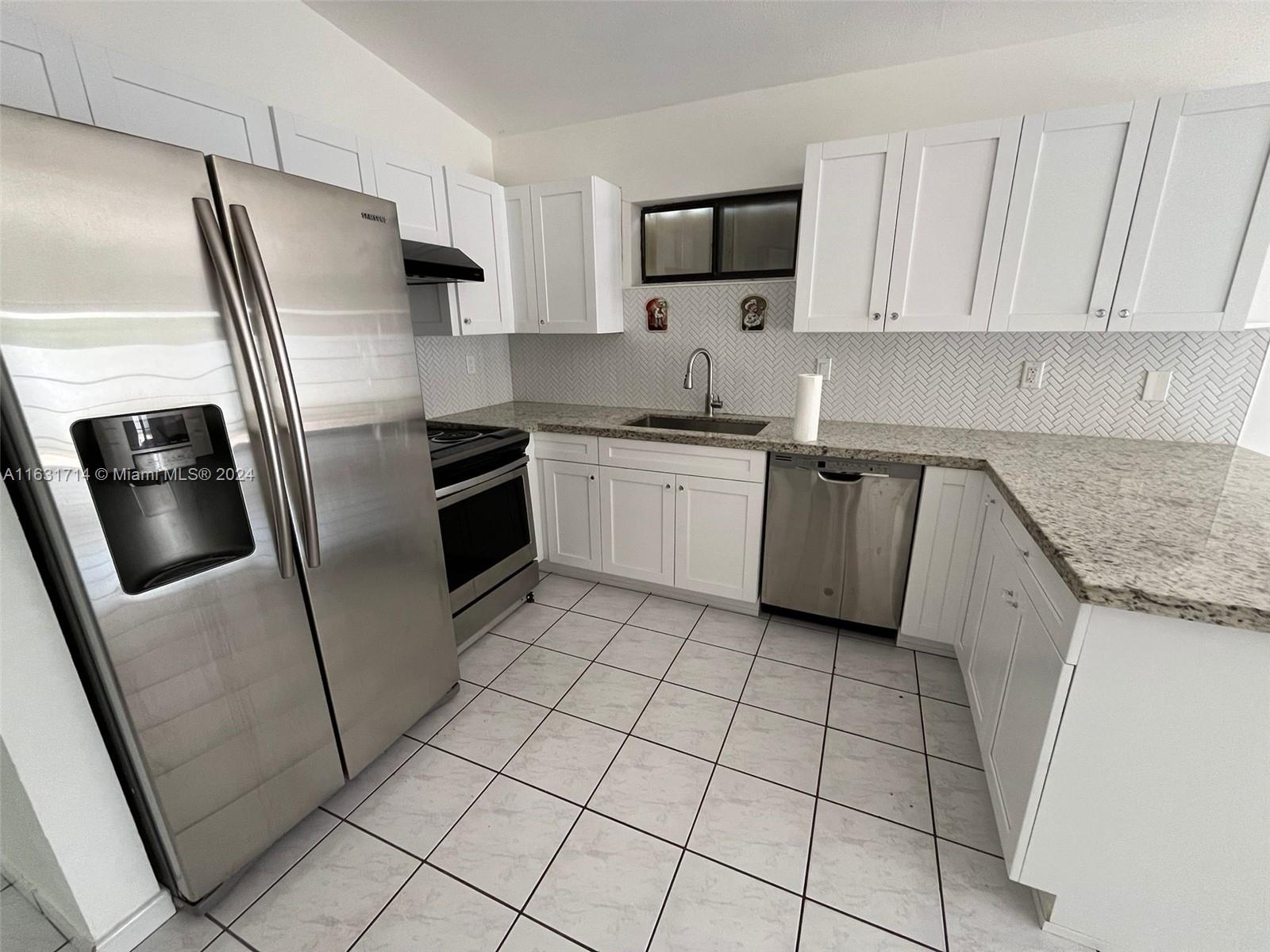 a kitchen with stainless steel appliances granite countertop a refrigerator sink and stove