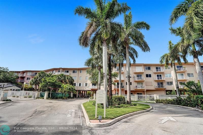 a view of a building with a yard and palm trees