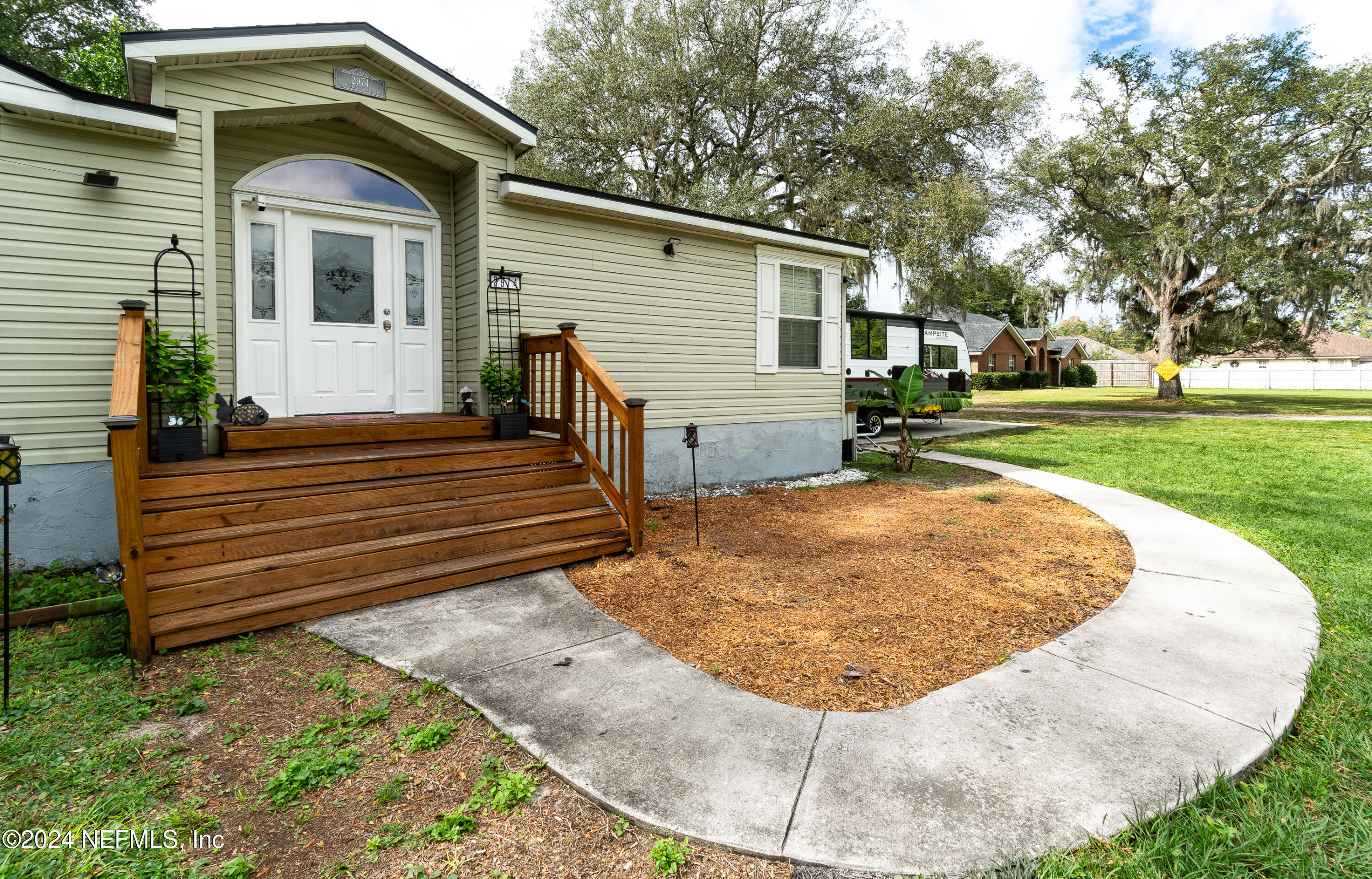 a view of a house with a small yard plants and large tree