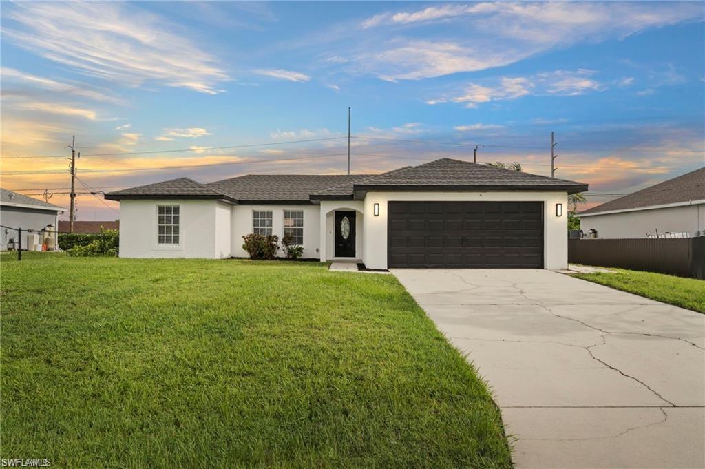 Ranch-style home featuring a lawn and a garage