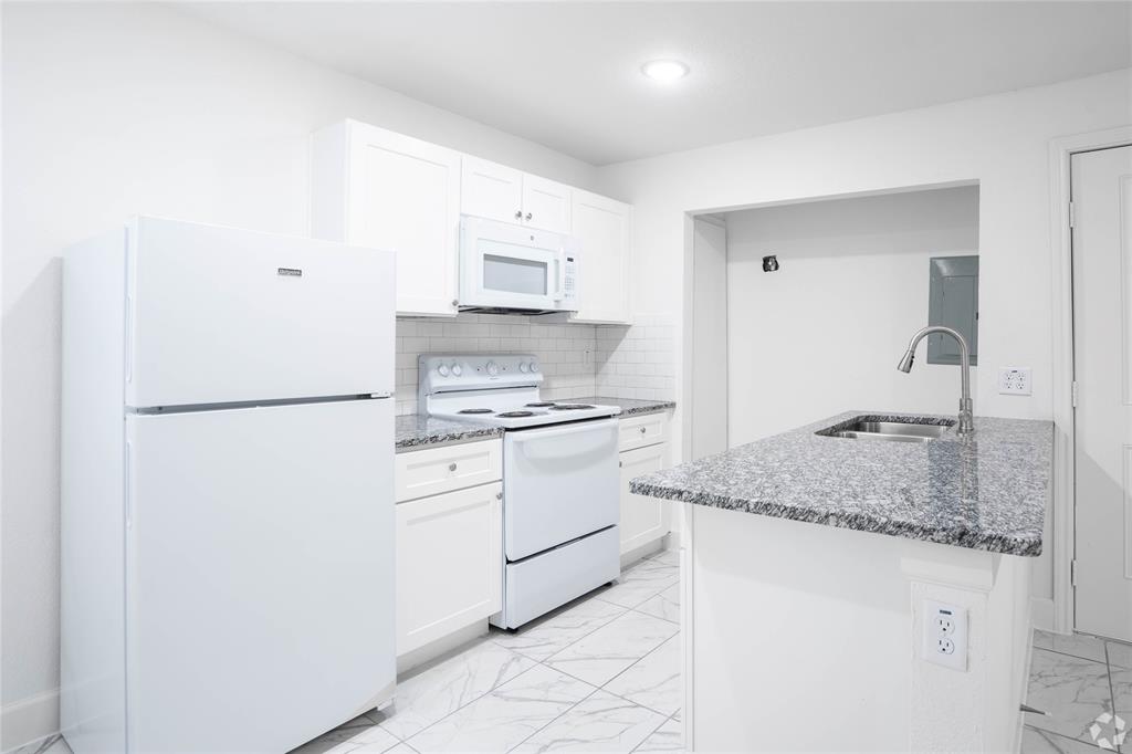 a kitchen with granite countertop white cabinets and white appliances