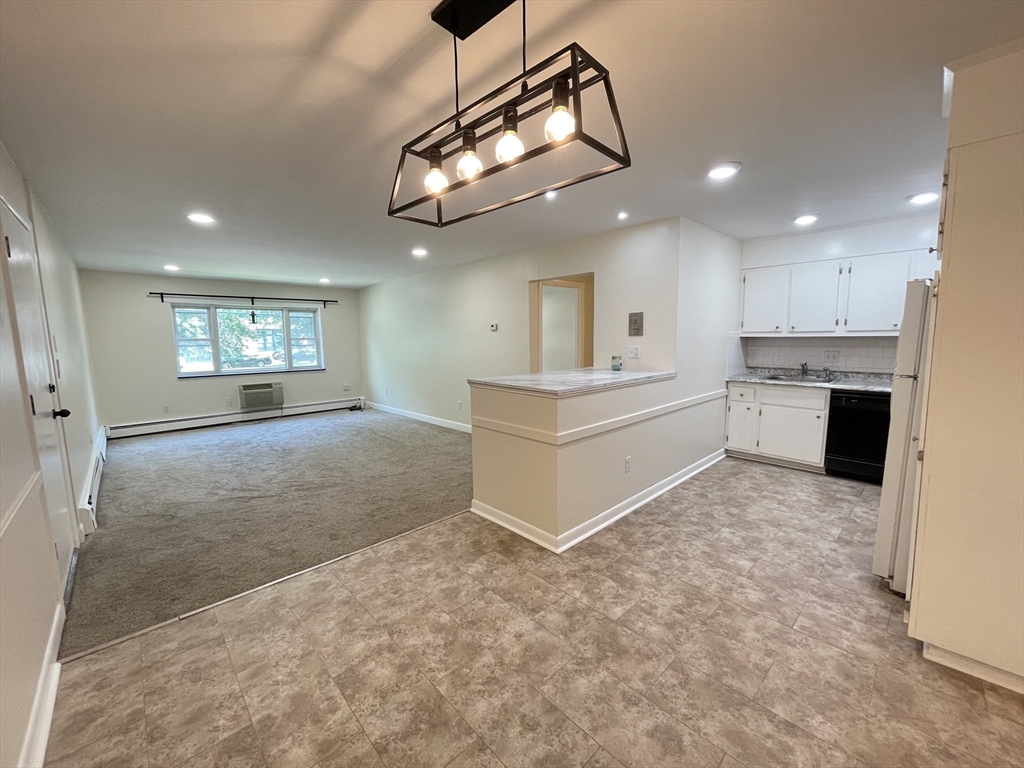 a large white kitchen with kitchen island a sink stainless steel appliances and cabinets