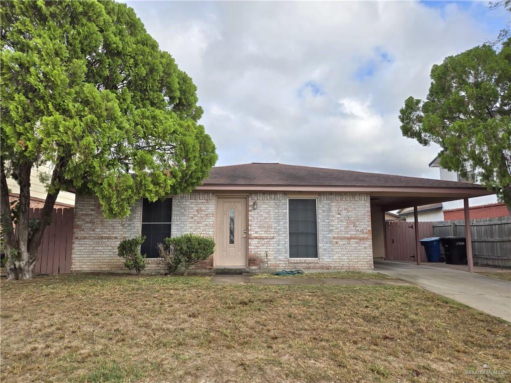 View of front of home with a front yard and a carport