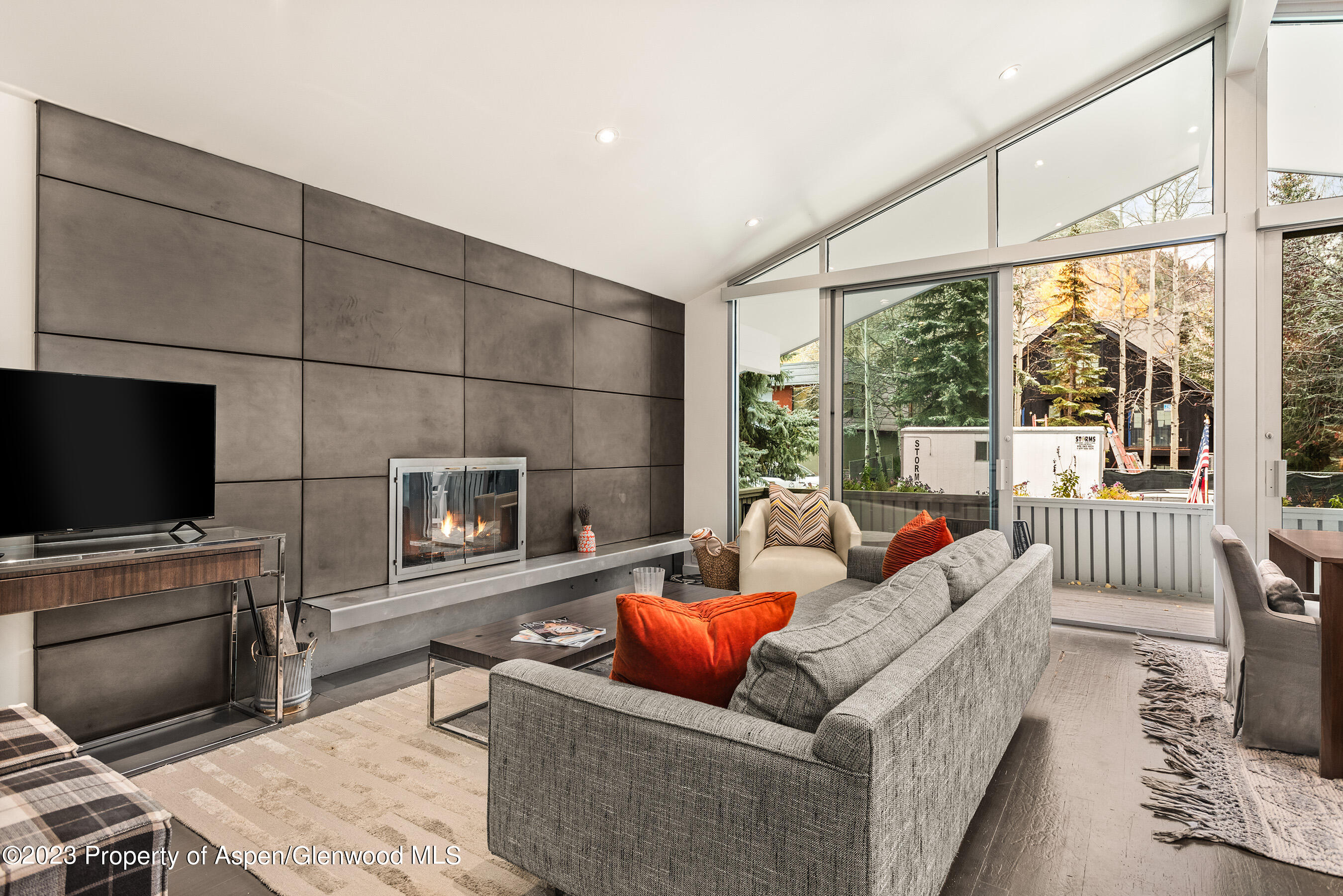 a living room with furniture a flat screen tv and a floor to ceiling window