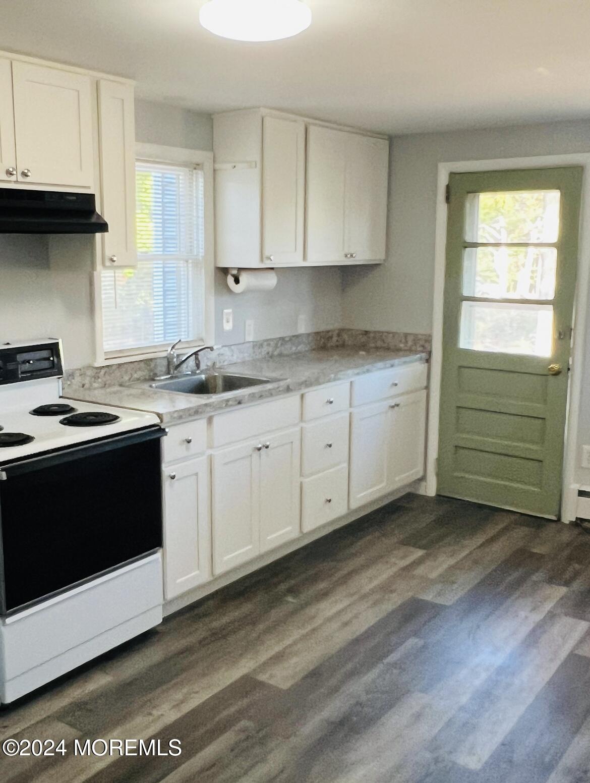 a kitchen with granite countertop a stove a sink and a microwave