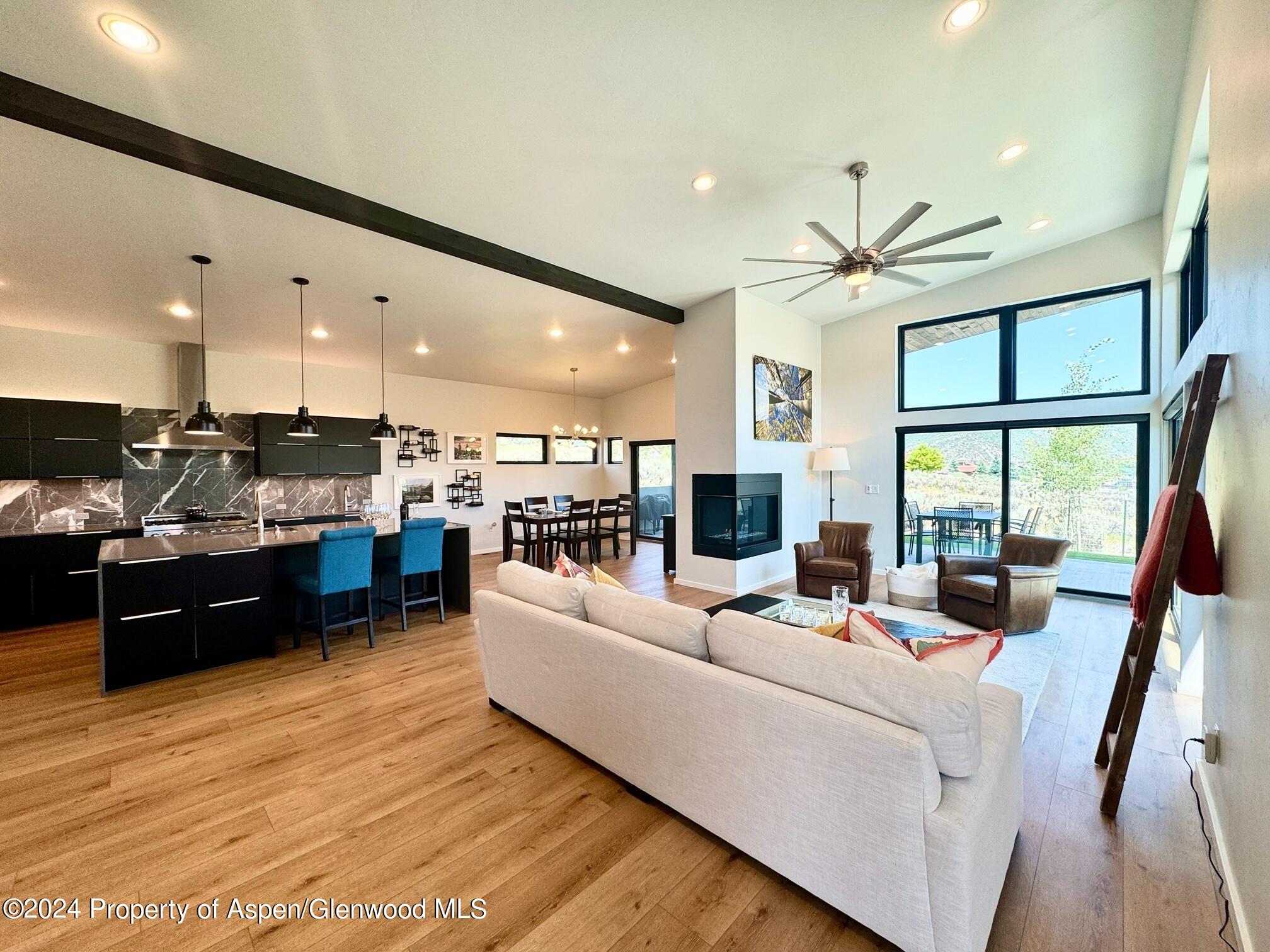 a living room with furniture kitchen area and a large window