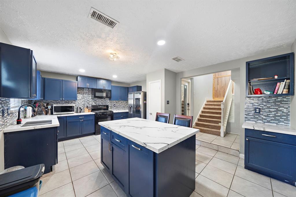 a large kitchen with stainless steel appliances kitchen island granite countertop a refrigerator and a stove top oven