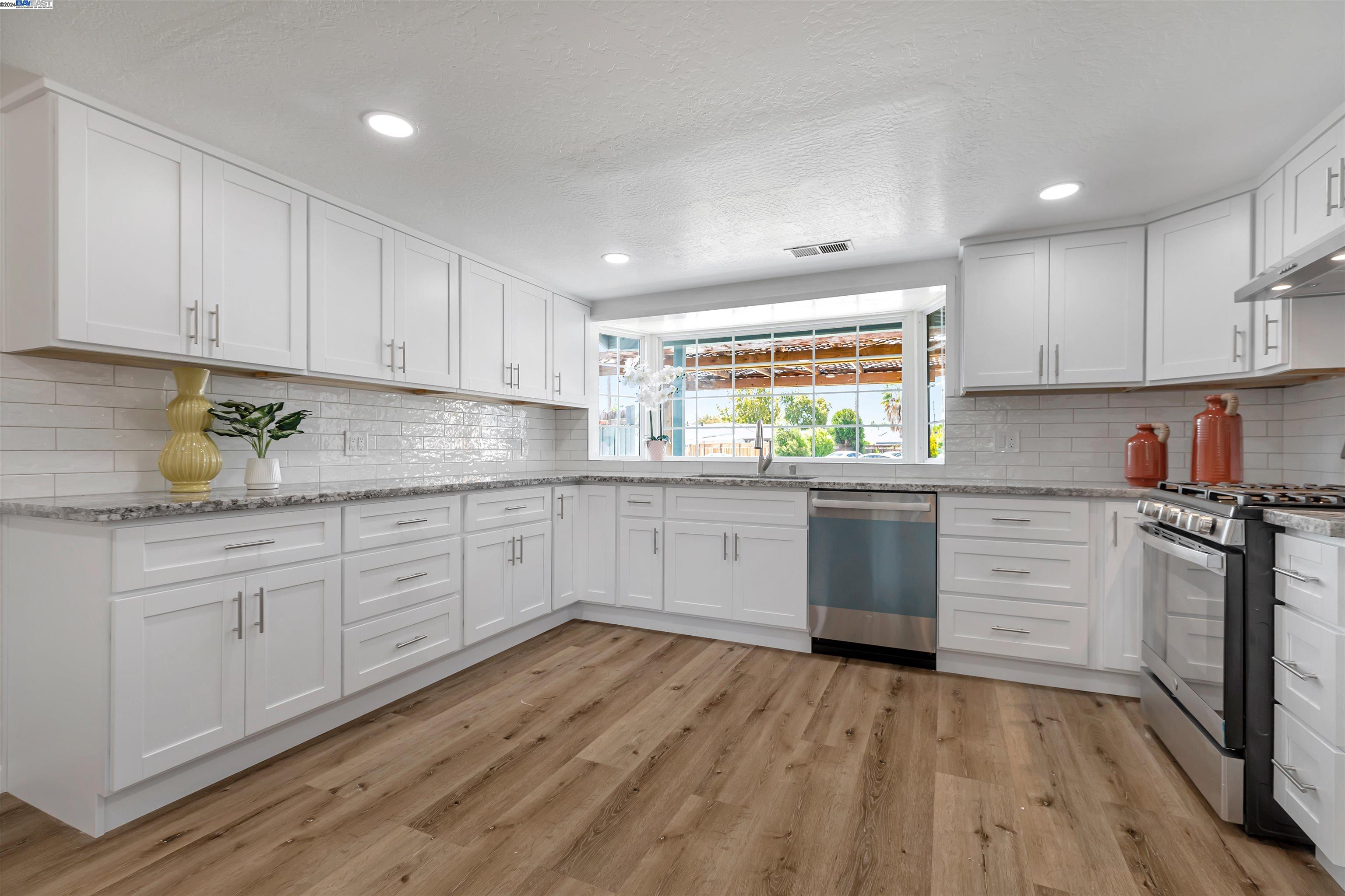 a kitchen with granite countertop white cabinets white stainless steel appliances and sink