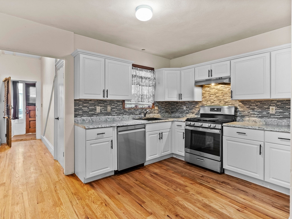 a kitchen with granite countertop a stove a sink and a refrigerator