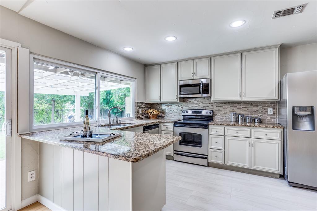 a kitchen with kitchen island granite countertop a stove sink and microwave