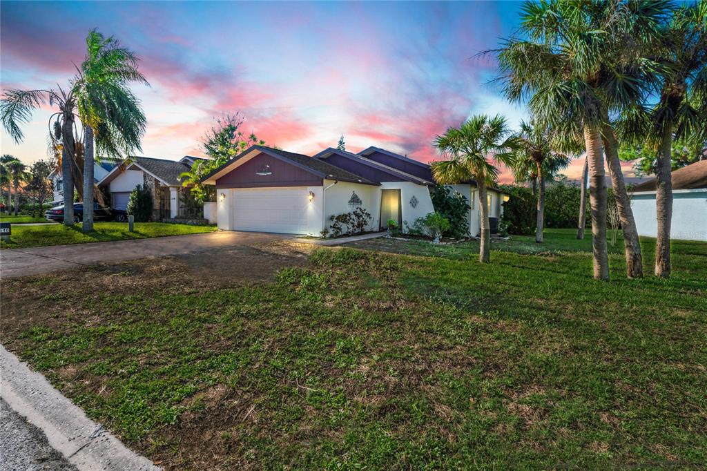 a front view of a house with a yard and palm trees