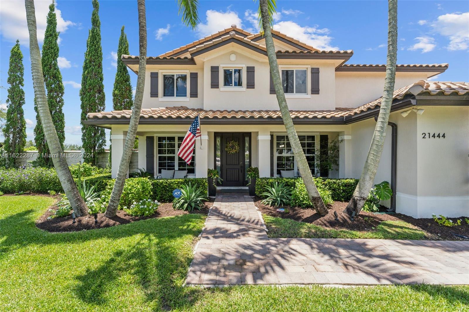 a front view of a house with a yard and potted plants