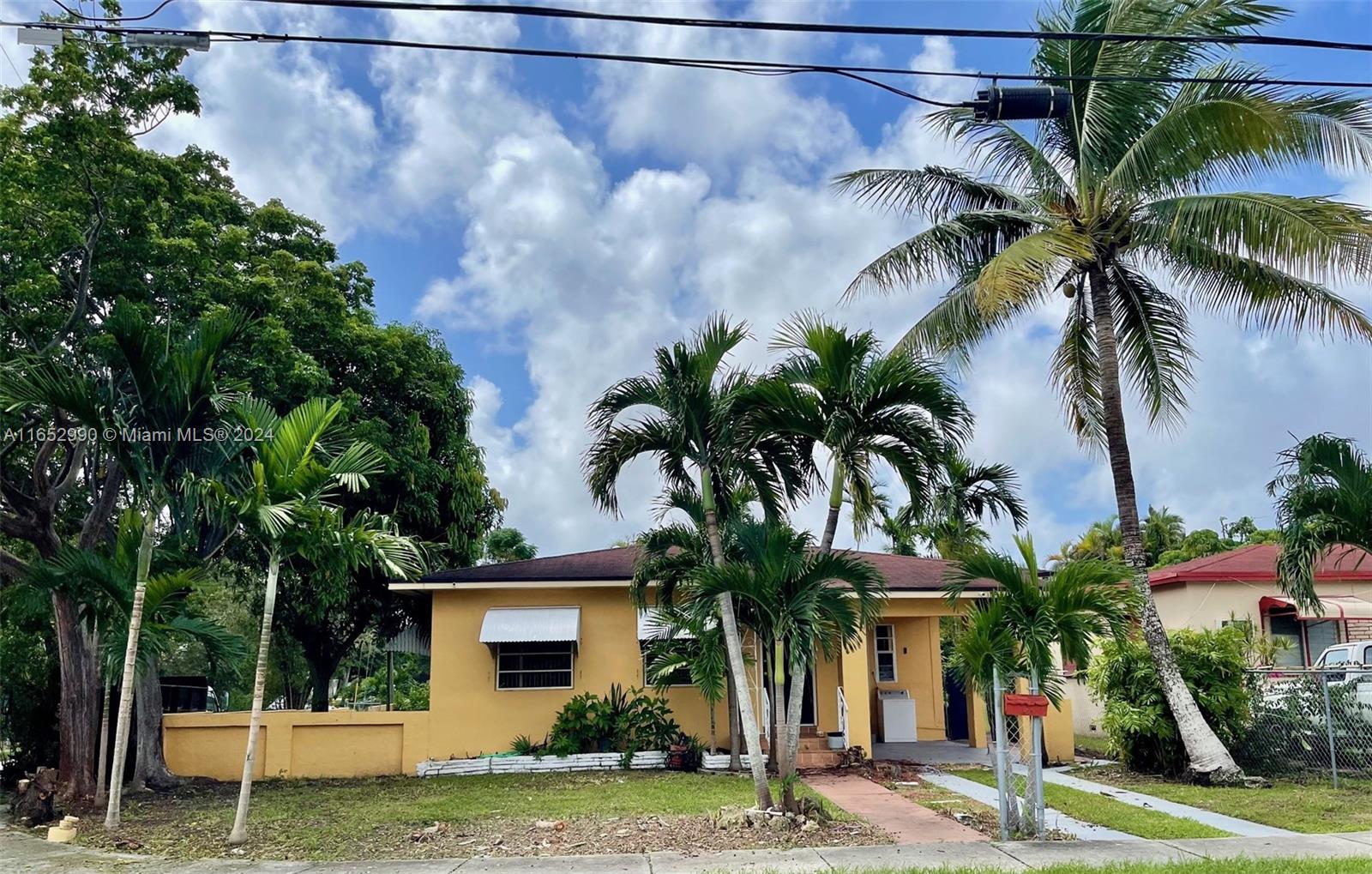 a view of a house with a yard and palm trees