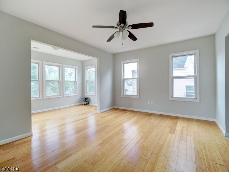 a view of an empty room with window and wooden floor