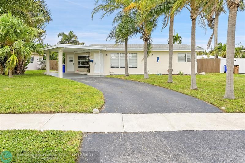 a view of a white house with a big yard and palm trees