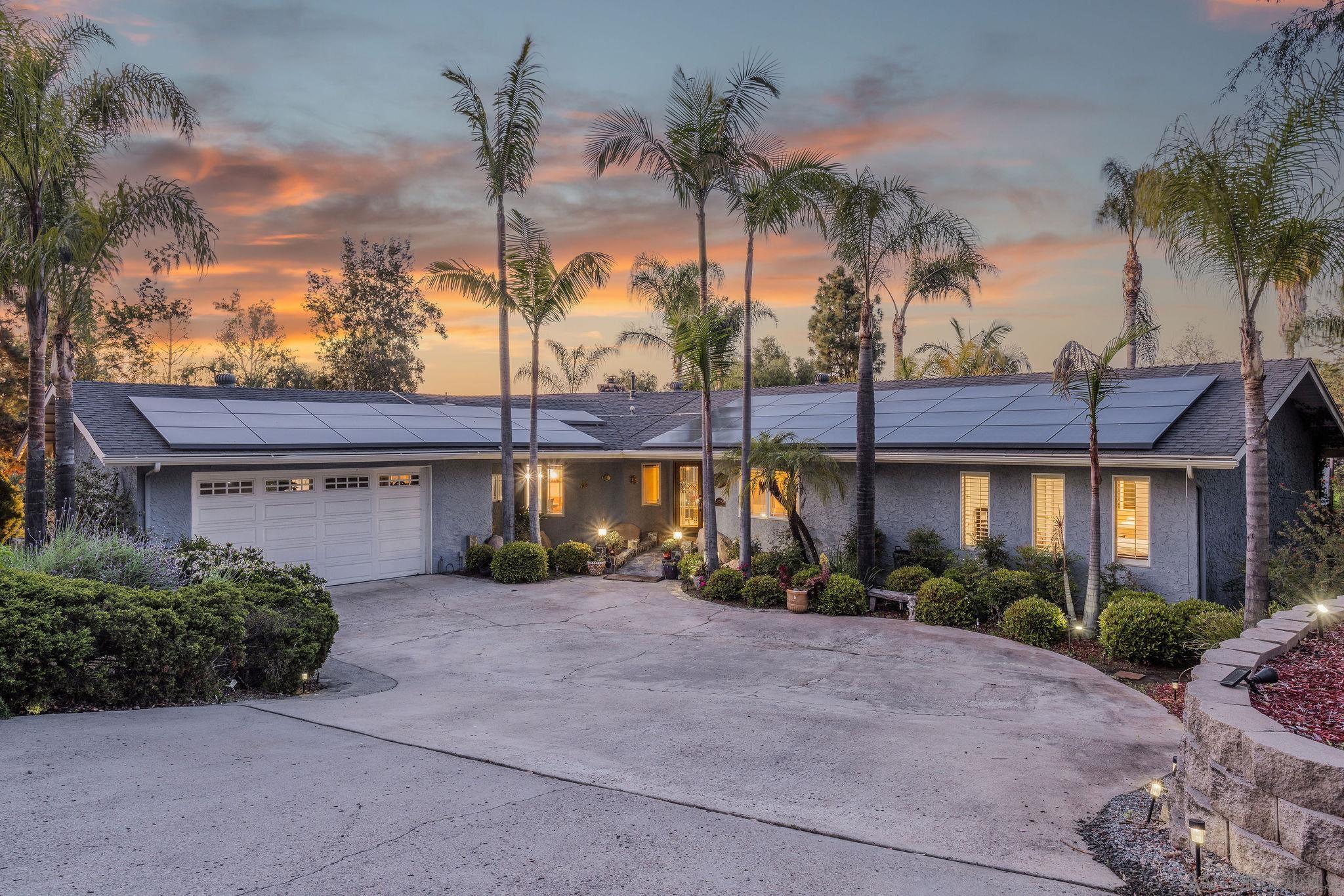 front view of a house with a yard and palm trees