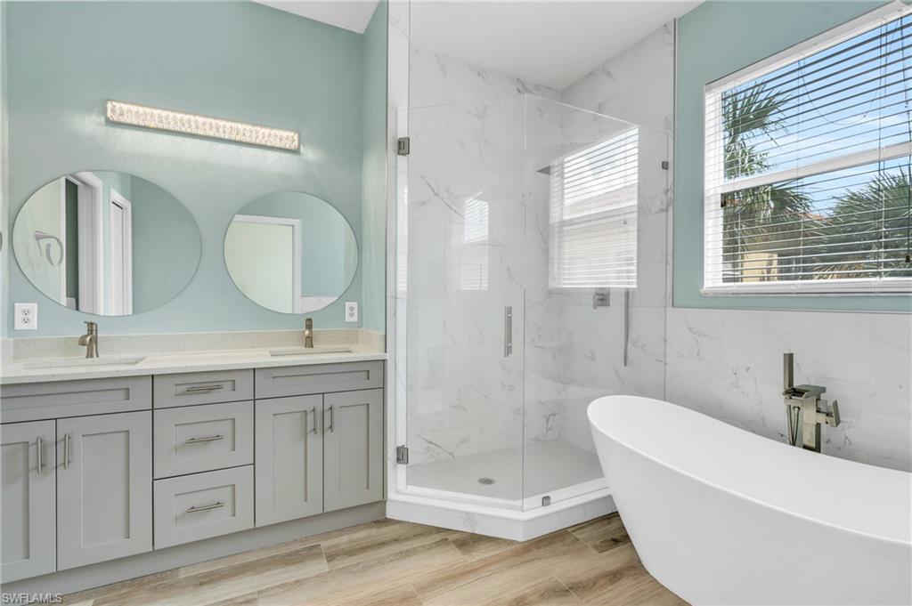 Bathroom with independent shower and bath, hardwood / wood-style flooring, vanity, and tile walls