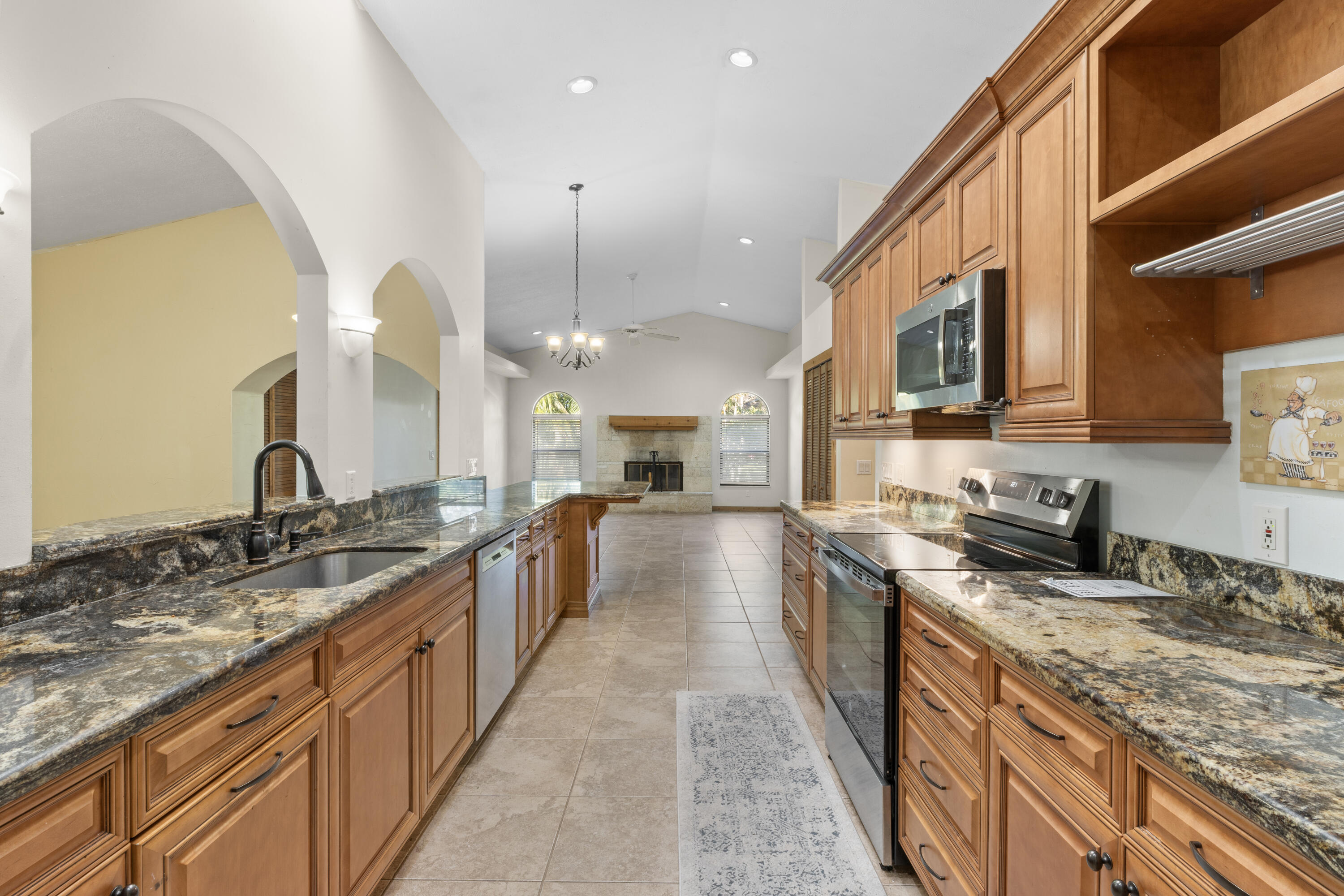 a large kitchen with granite countertop a large counter top a sink stainless steel appliances and cabinets