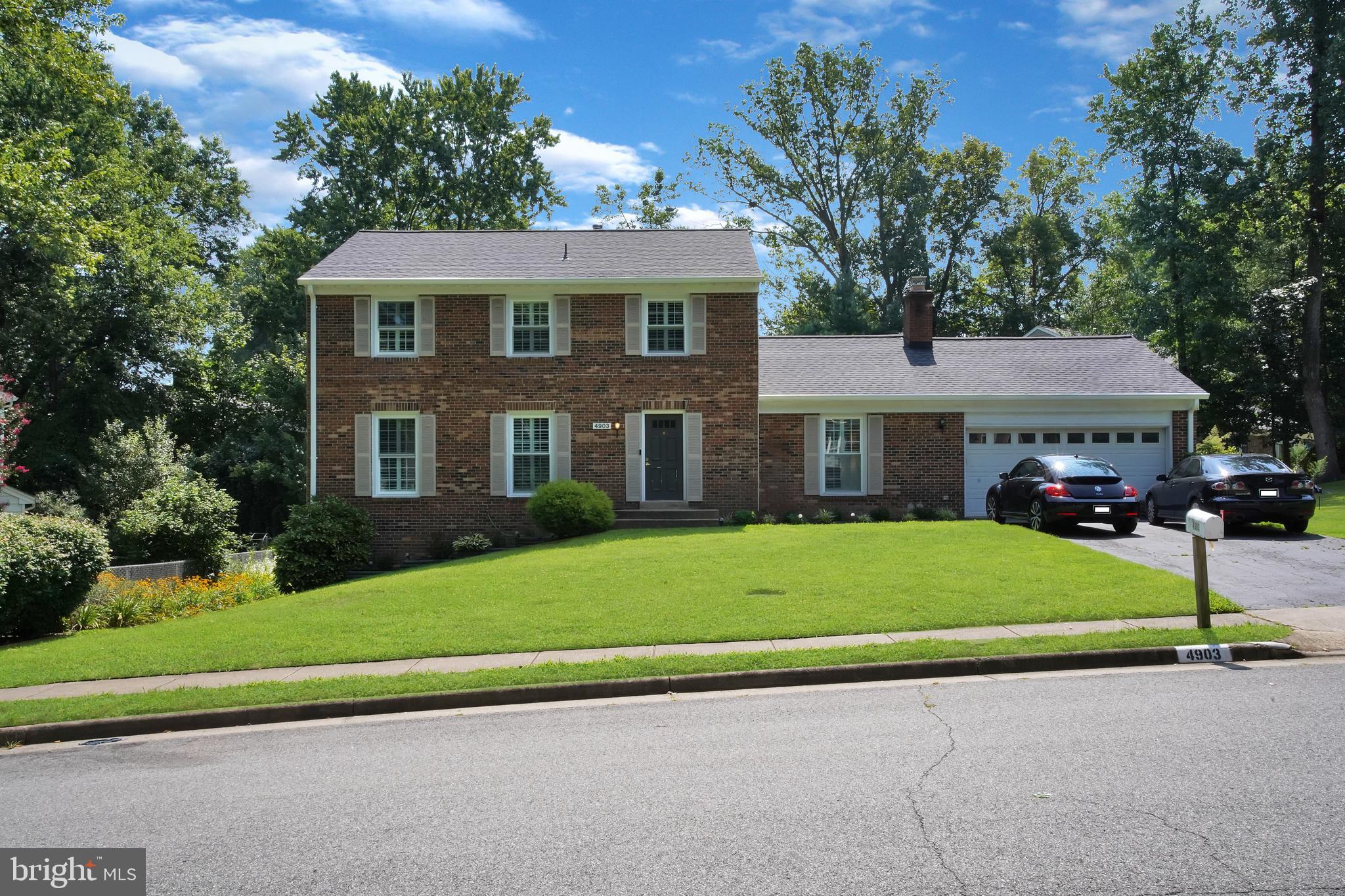 a front view of a house with a garden and trees