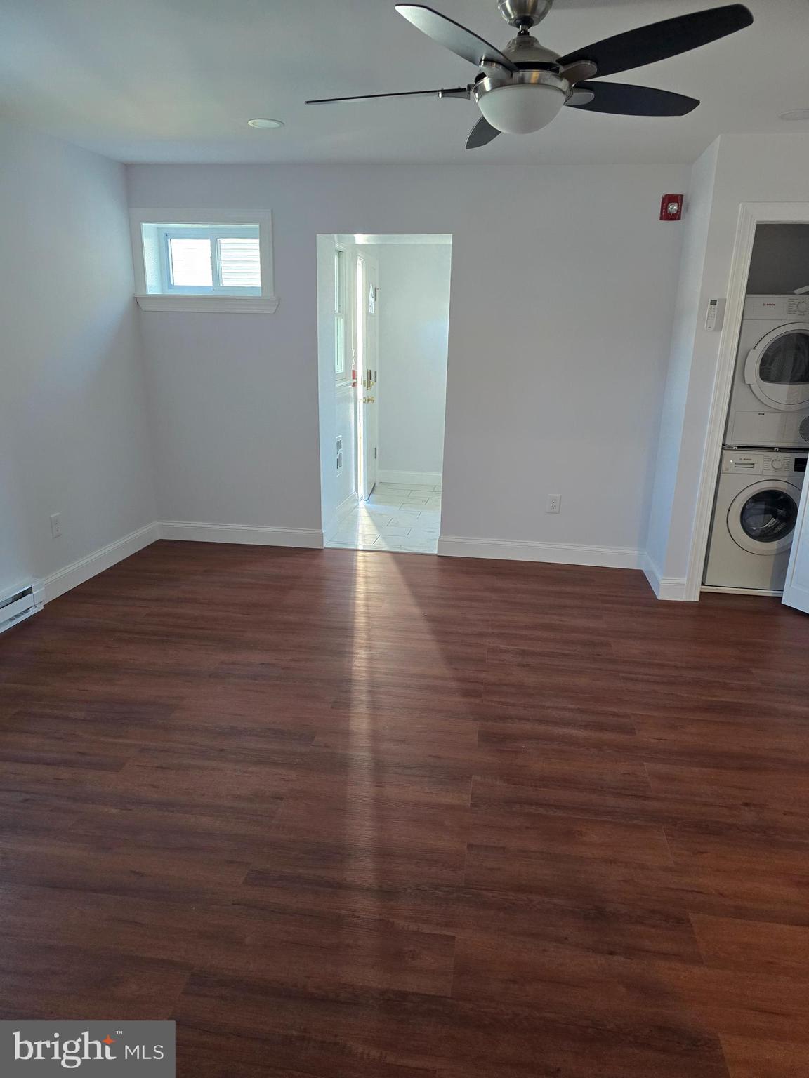 a view of an empty room with a window and wooden floor