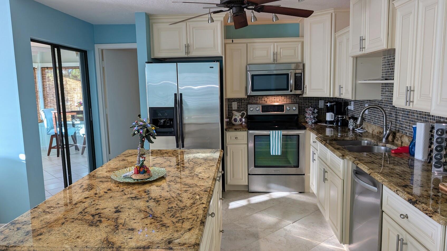 a kitchen with stainless steel appliances kitchen island granite countertop a refrigerator and a stove top oven