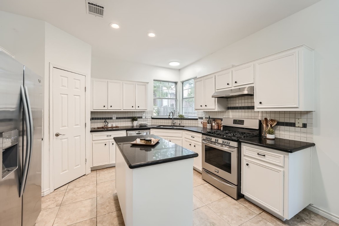 a kitchen with white cabinets and stainless steel appliances