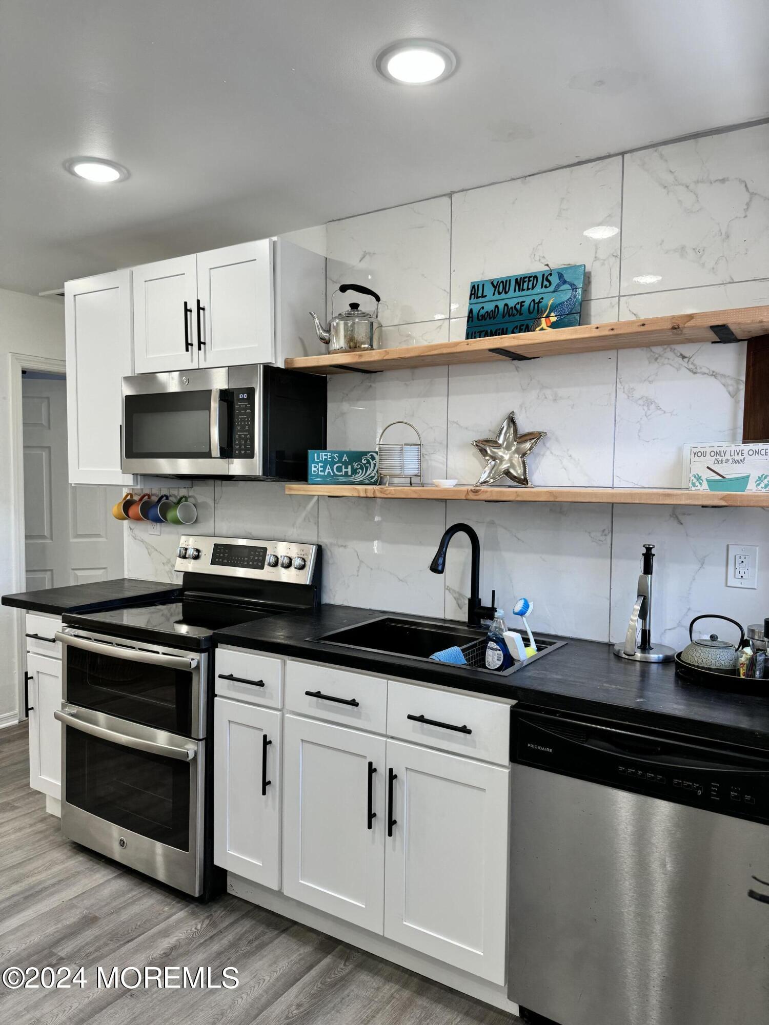 a kitchen with stainless steel appliances granite countertop a sink a stove and cabinets