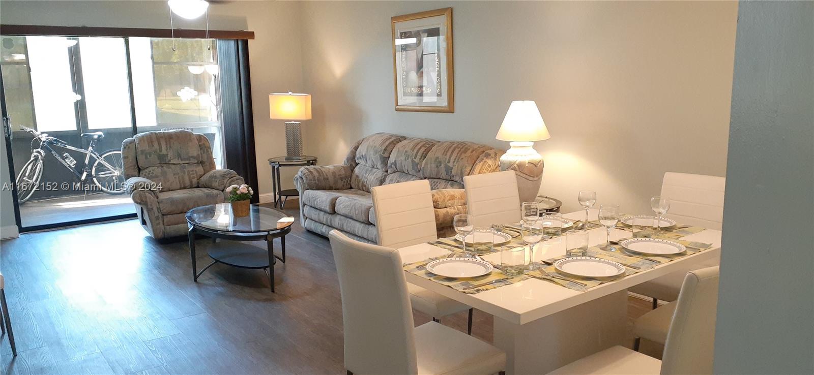 a living room with furniture a lamp wooden floor and a large window